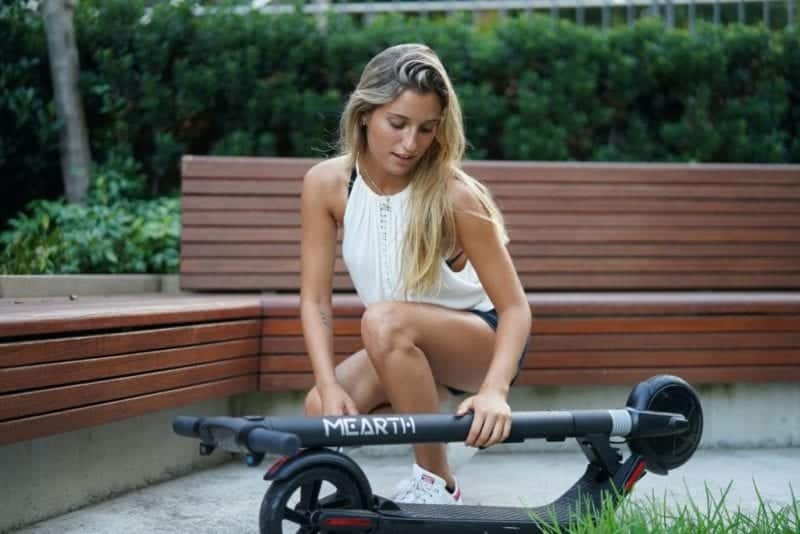 woman in white tank top while holding folded electric 3803856 scaled